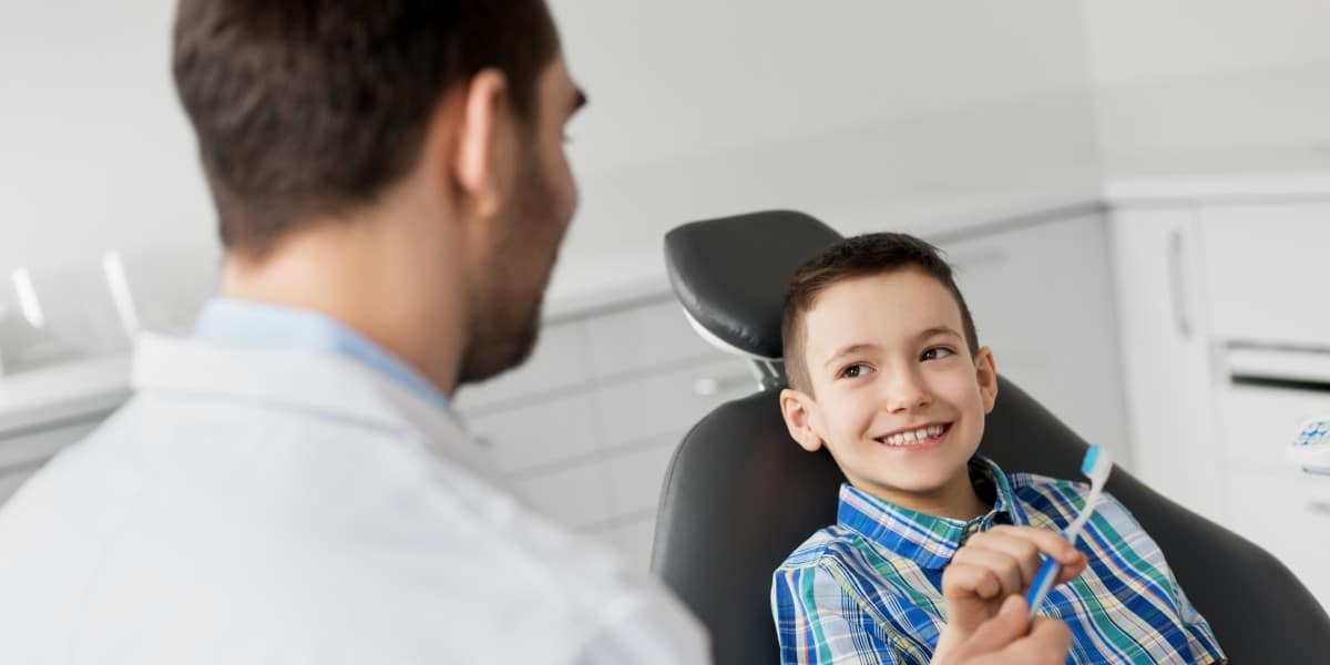 Young boy smiling at dentist during checkup in dental office setting.