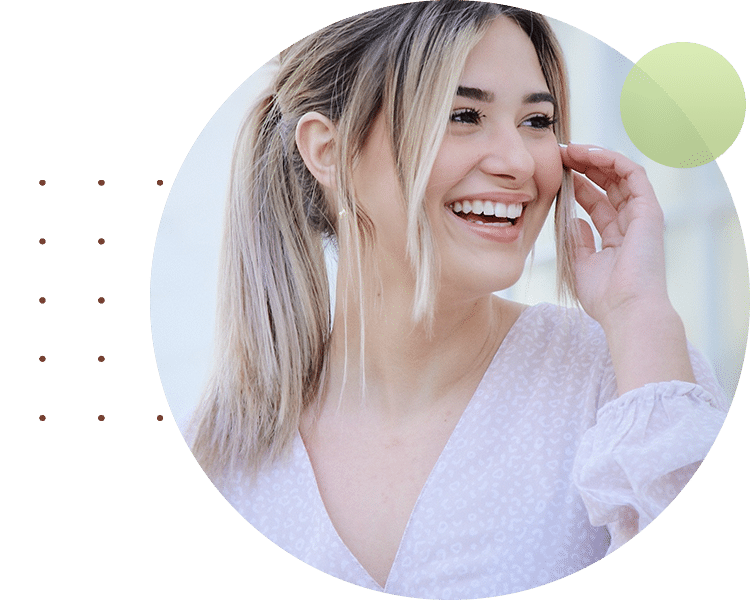 Smiling woman in white sweater touching face, representing dental health and wellness care