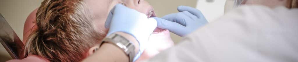 Dentist examining patient's teeth during dental checkup in clinical setting.