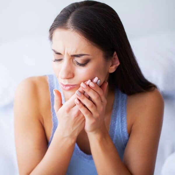 woman holding the side of her mouth