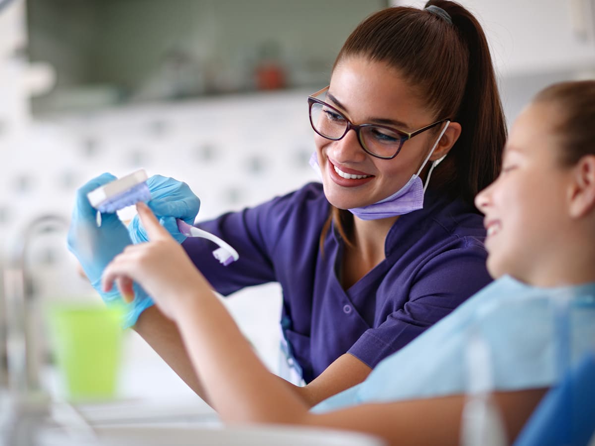 Image of a girl showing a kid how to brush