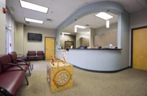 Modern dental office reception area with curved desk, waiting chairs, and professional lighting.