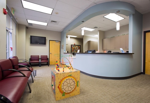 Modern dental office reception area with waiting room seating and front desk counter.