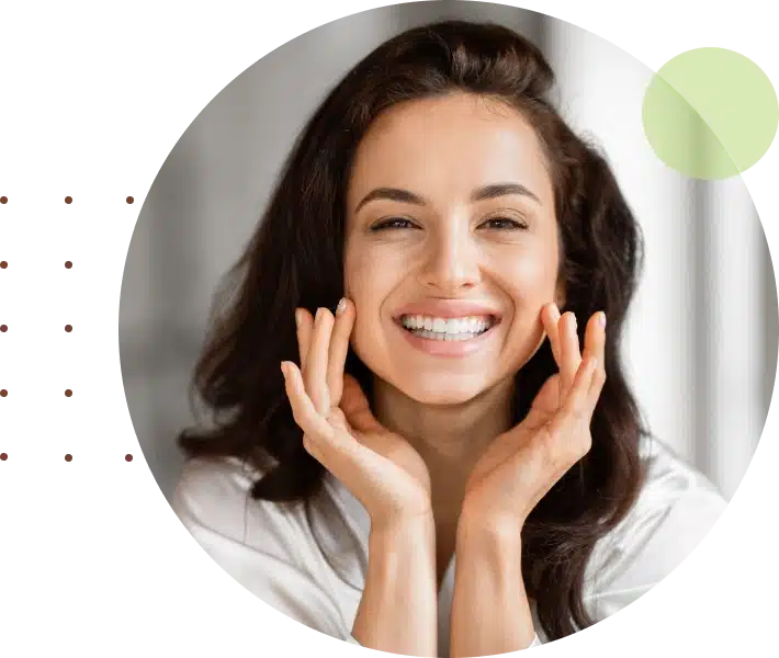 Smiling woman with hands to face in bright clinical setting, promoting dental care and wellness.