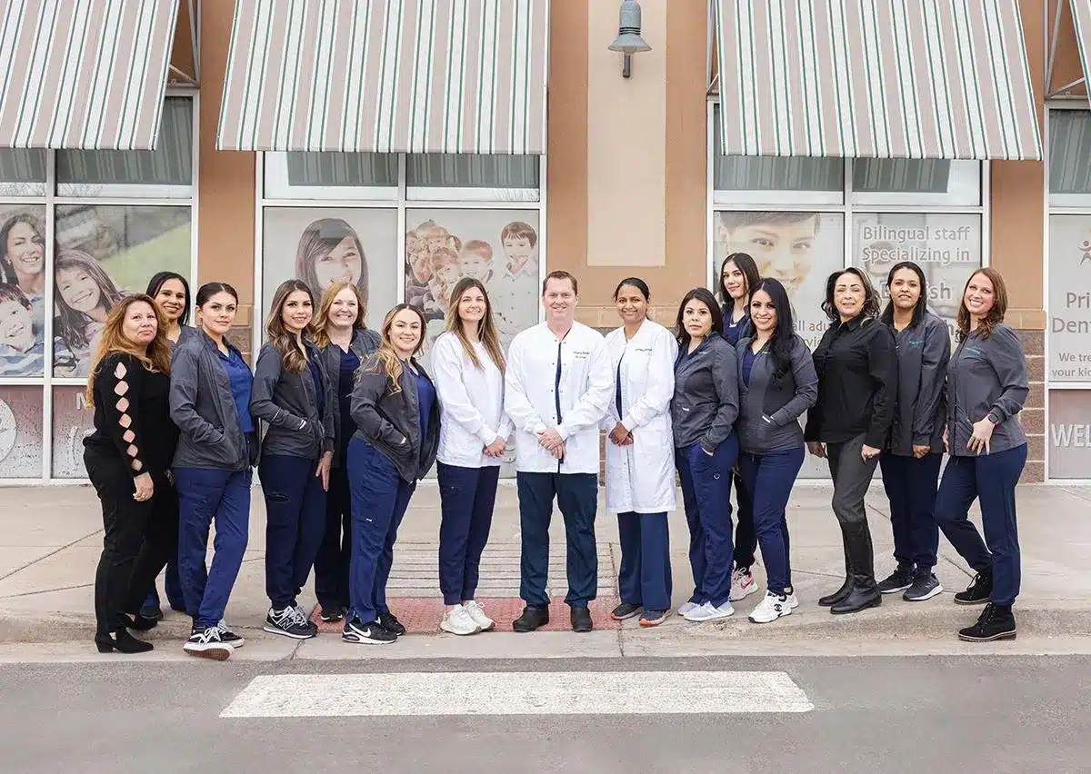 Dental team of professionals posing together outside modern clinic building