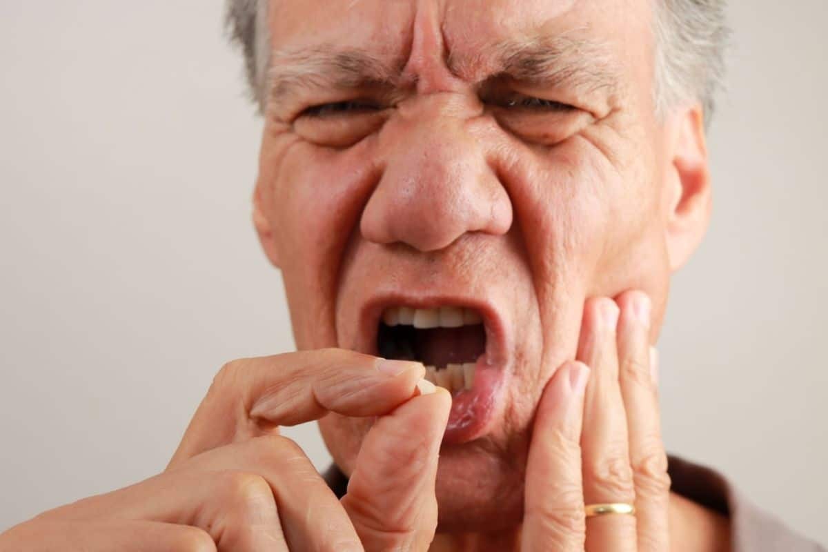 Man experiencing tooth pain, holding his cheek in discomfort.