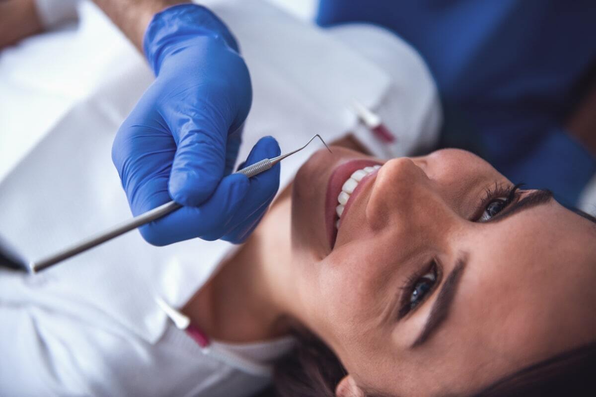 Dentist examining patient's teeth with dental mirror during oral examination.