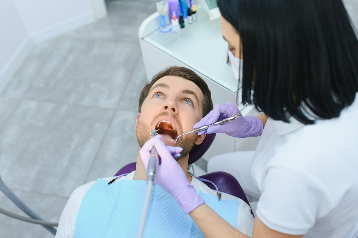 Dentist examining patient's teeth during oral examination in dental office.