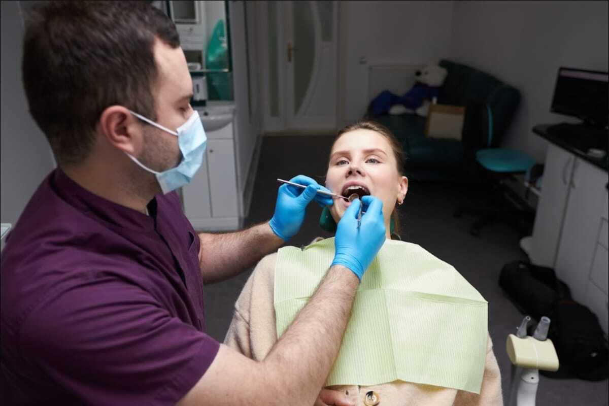 Dental hygienist performing teeth cleaning on patient at Denver, CO dental practice.