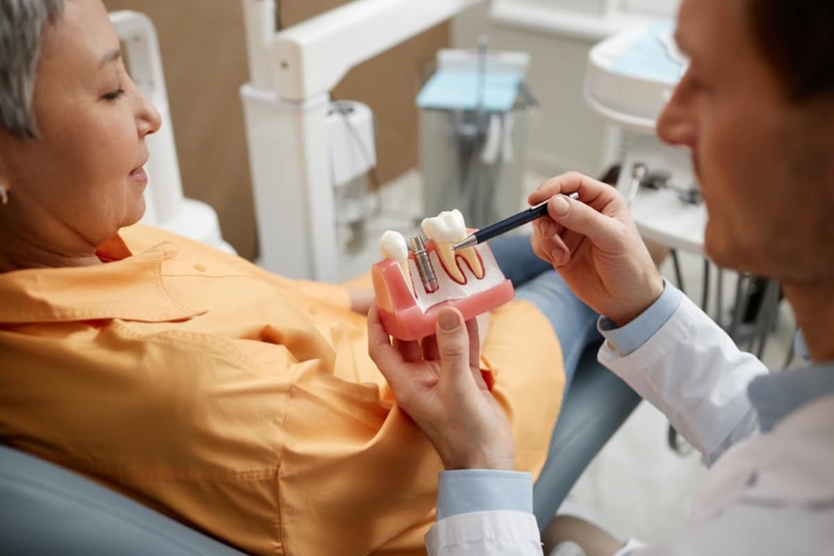 Dentist explaining dental implant model to patient at Denver dental office on W 44th Ave.